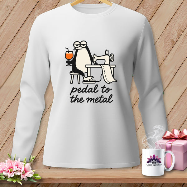 White long-sleeve shirt with penguin sewing, holding drink, and text "pedal to the metal."