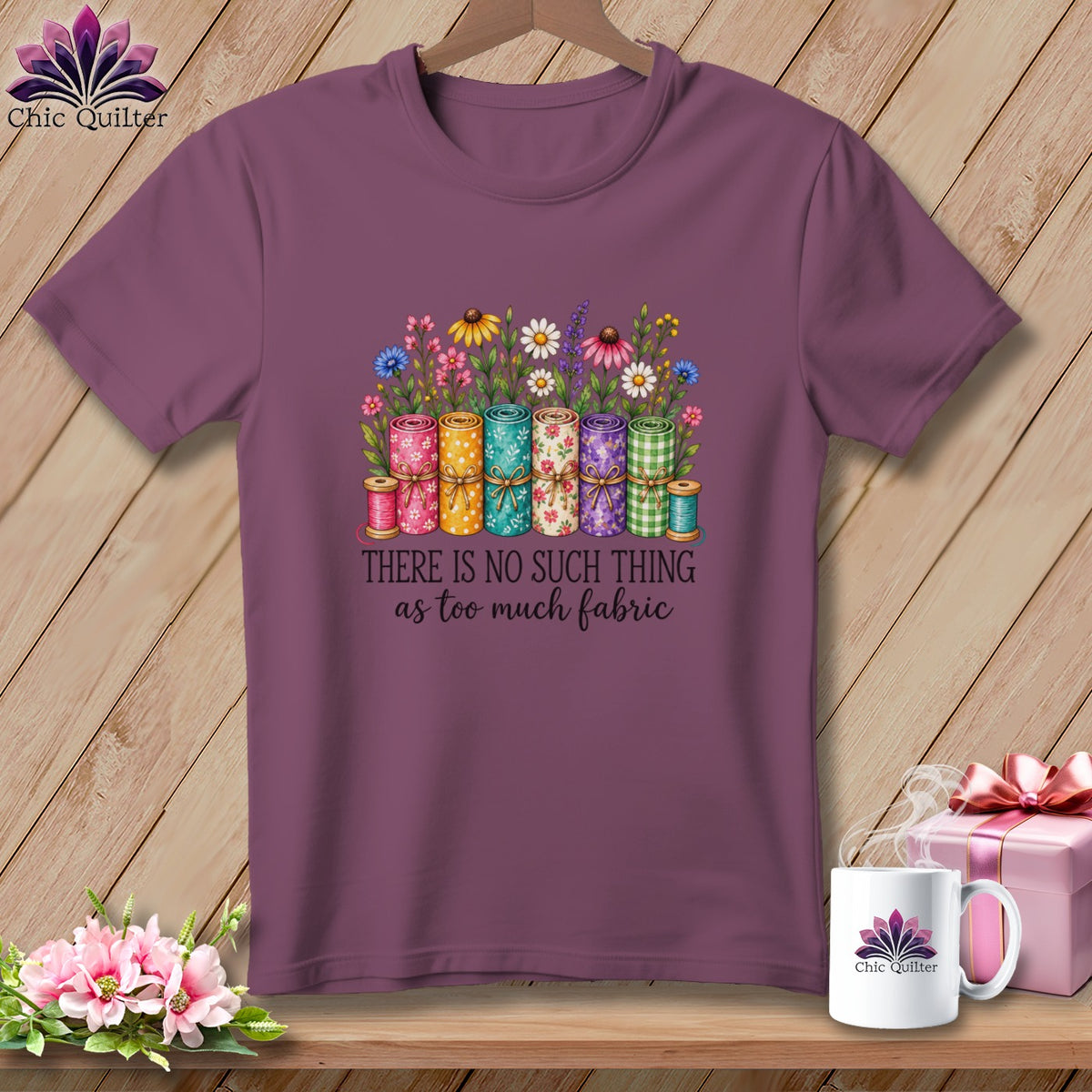 Mauve short-sleeve t-shirt with a colorful graphic of rolled fabric, flowers, and the text "There is no such thing as too much fabric."