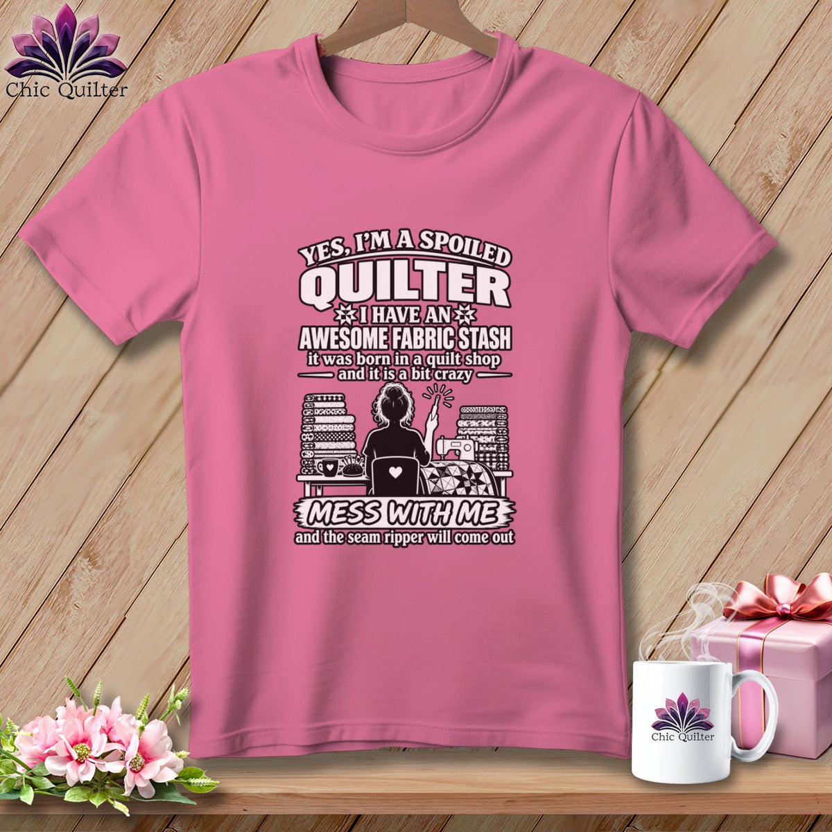 Pink t-shirt with text about being a spoiled quilter, graphic of a quilter, and white mug.