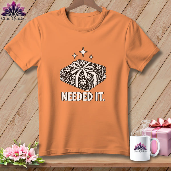 Orange t-shirt with stacked fabric bundle design and "NEEDED IT." text.