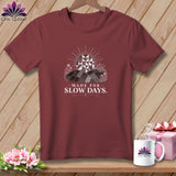 Maroon t-shirt with a graphic of a quilt-like landscape and text 