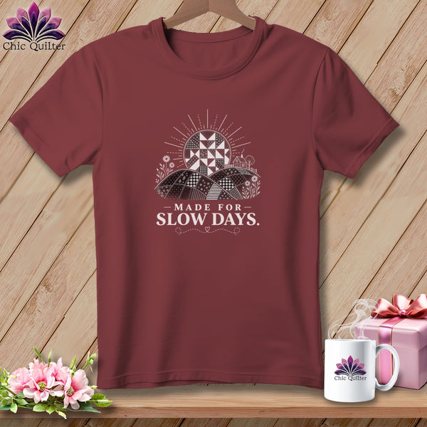 Maroon t-shirt with a graphic of a quilt-like landscape and text "MADE FOR SLOW DAYS."