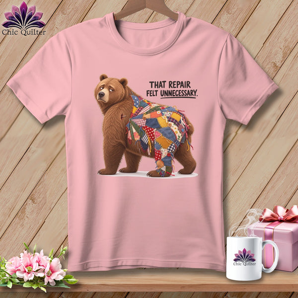 Pink t-shirt with bear patched with colorful quilt squares and text "THAT REPAIR FELT UNNECESSARY".