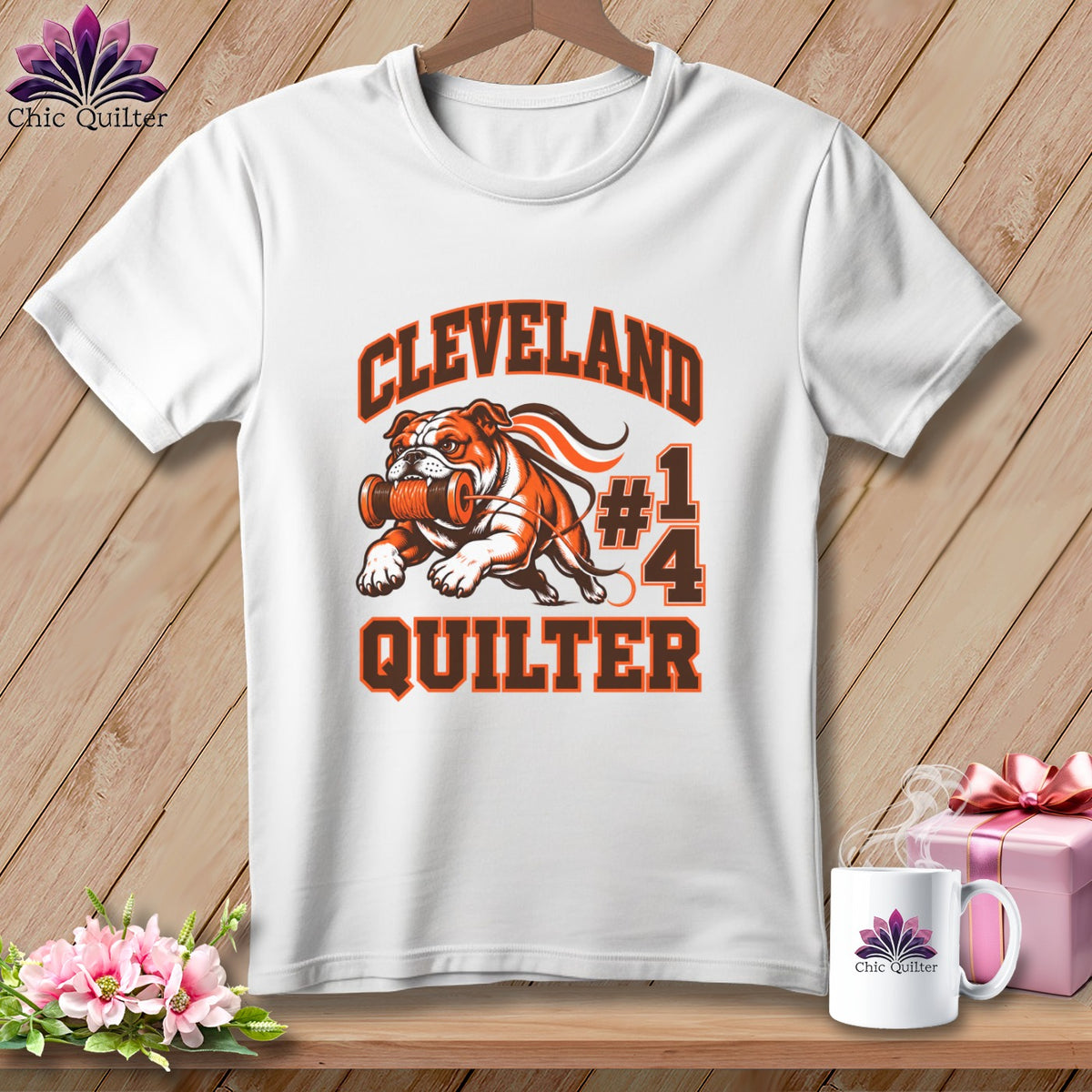 A white t-shirt features a Cleveland Quilter graphic of a bulldog holding a spool of thread.