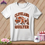 A white t-shirt features a Cleveland Quilter graphic of a bulldog holding a spool of thread.