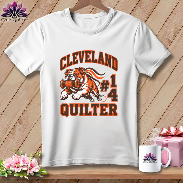 A white t-shirt features a Cleveland Quilter graphic of a bulldog holding a spool of thread.