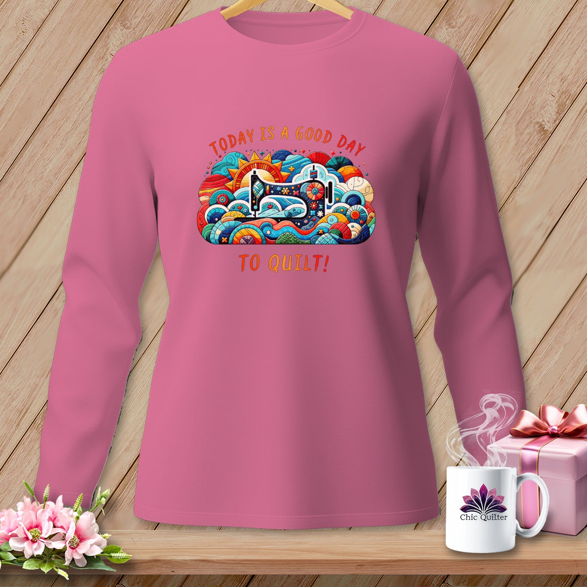 Pink long-sleeve shirt with colorful quilt design and text "TODAY IS A GOOD DAY TO QUILT!".