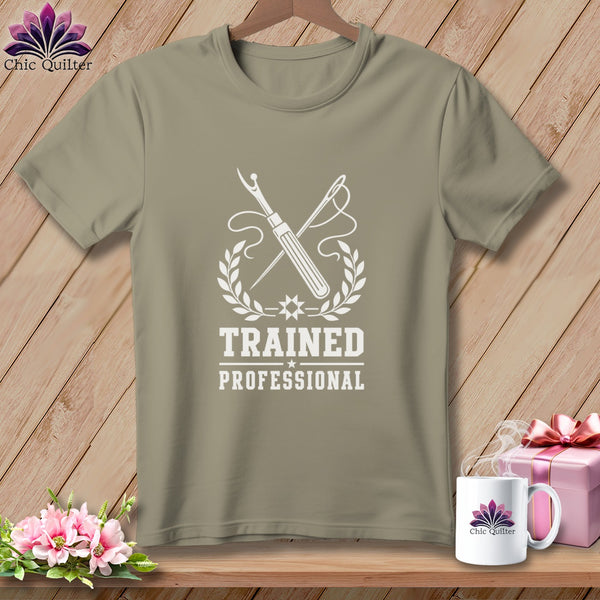 T-shirt with white graphic of sewing tools, wreath, and text "TRAINED PROFESSIONAL".