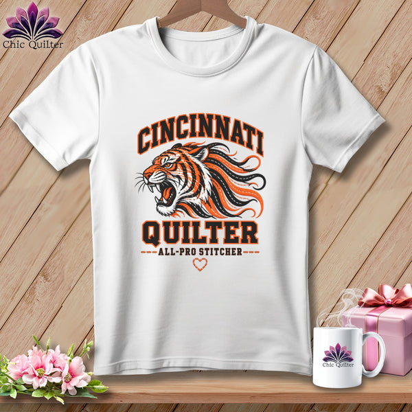 A white t-shirt featuring a roaring tiger graphic with orange and black text that reads Cincinnati Quilter All-Pro Stitcher.