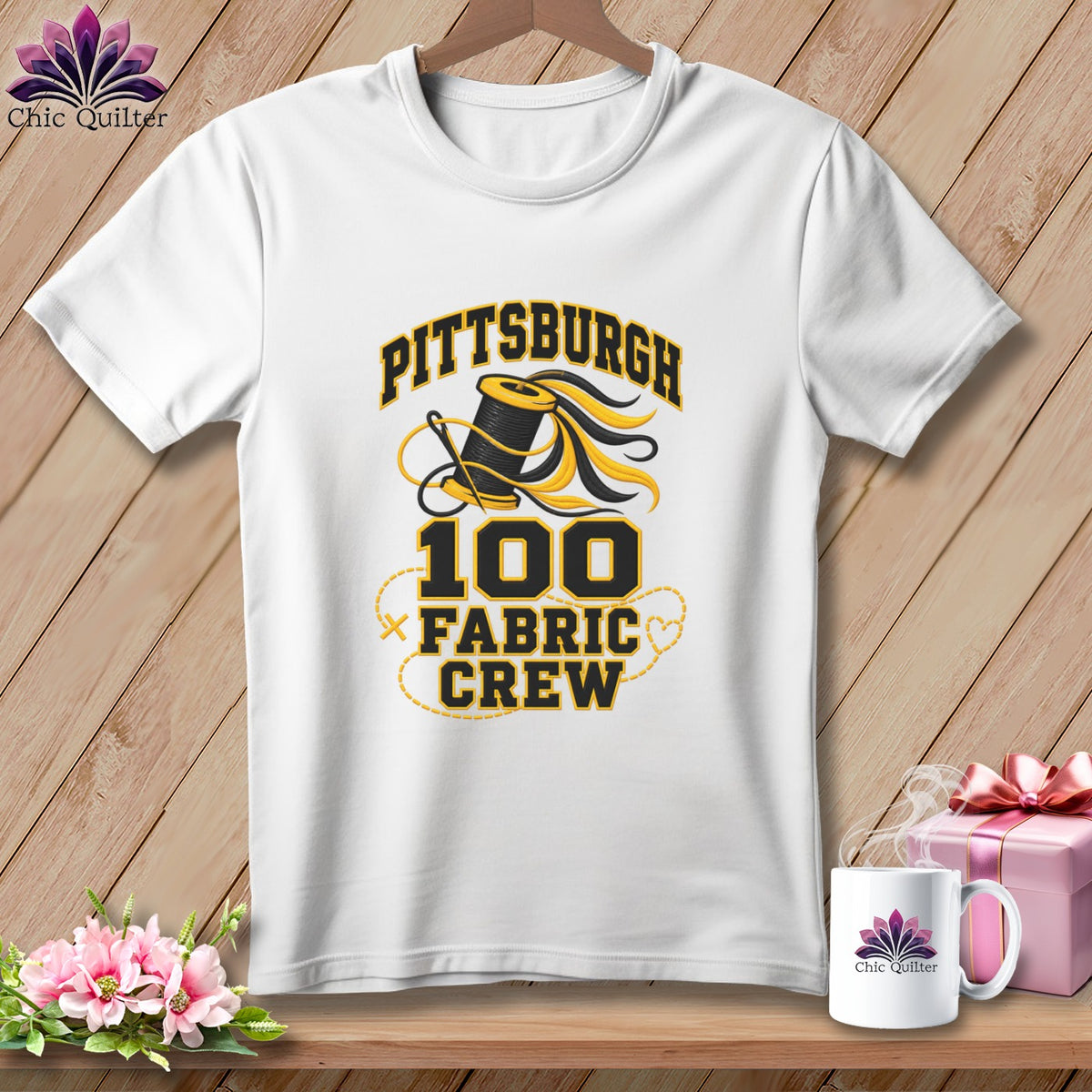 A white crewneck t-shirt featuring a Pittsburgh 100 Fabric Crew graphic with a spool of thread.