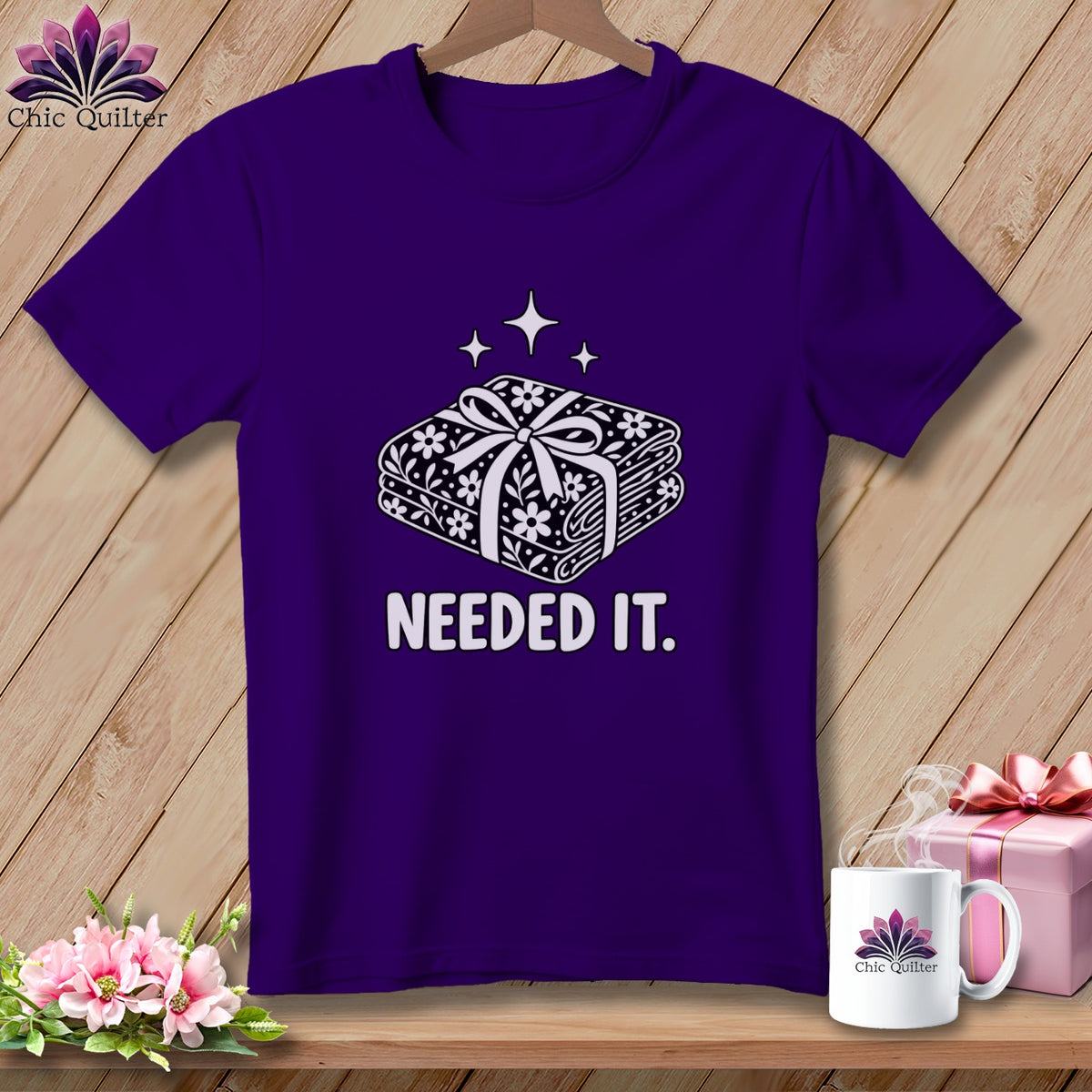 Purple t-shirt with graphic of stacked fabric rolls and text "NEEDED IT."