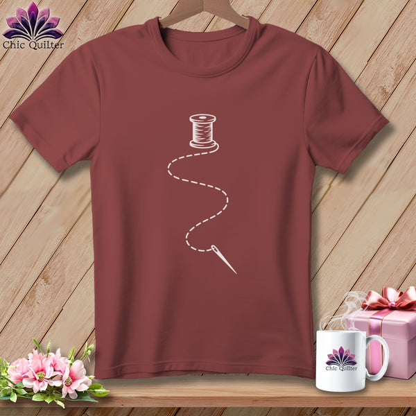 Maroon t-shirt with a white spool of thread and needle graphic.