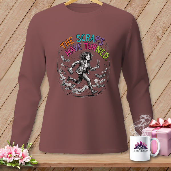 Long-sleeve shirt with graphic of woman running, scissors, bats, and text "The Scraps Have Turned."