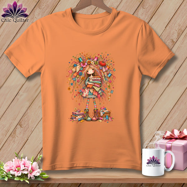 An orange crew neck t-shirt featuring a whimsical illustration of a sewing girl on a wooden background.
