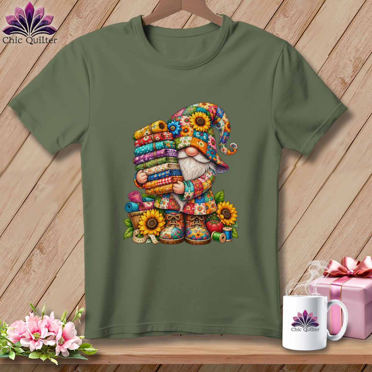 An olive green t-shirt displays a colorful graphic of a gnome holding a stack of folded fabrics.