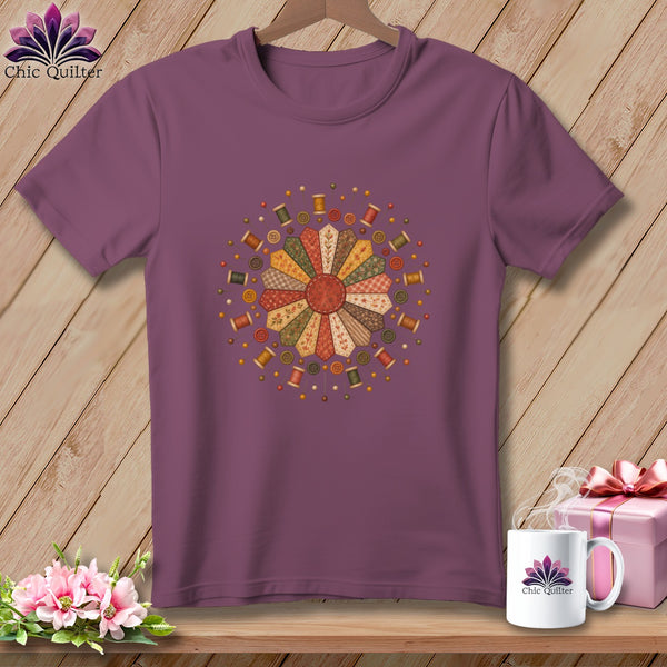 Plum t-shirt with a quilted flower design, spools of thread, and buttons.