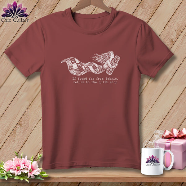 Maroon t-shirt with a whimsical mermaid holding a quilt, and text about returning to the quilt shop.
