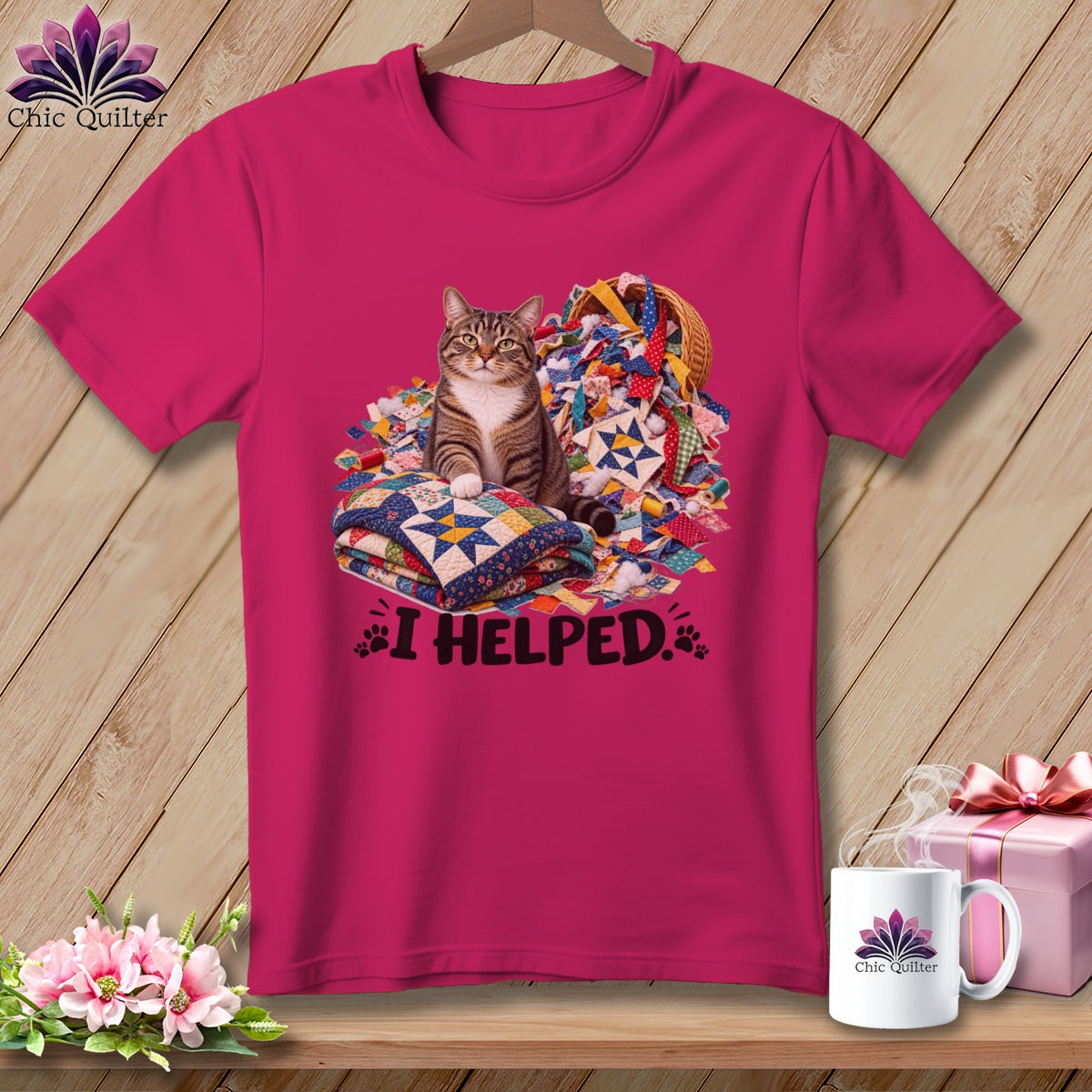 Pink t-shirt with a cat sitting on quilts and fabric scraps, saying "I HELPED."