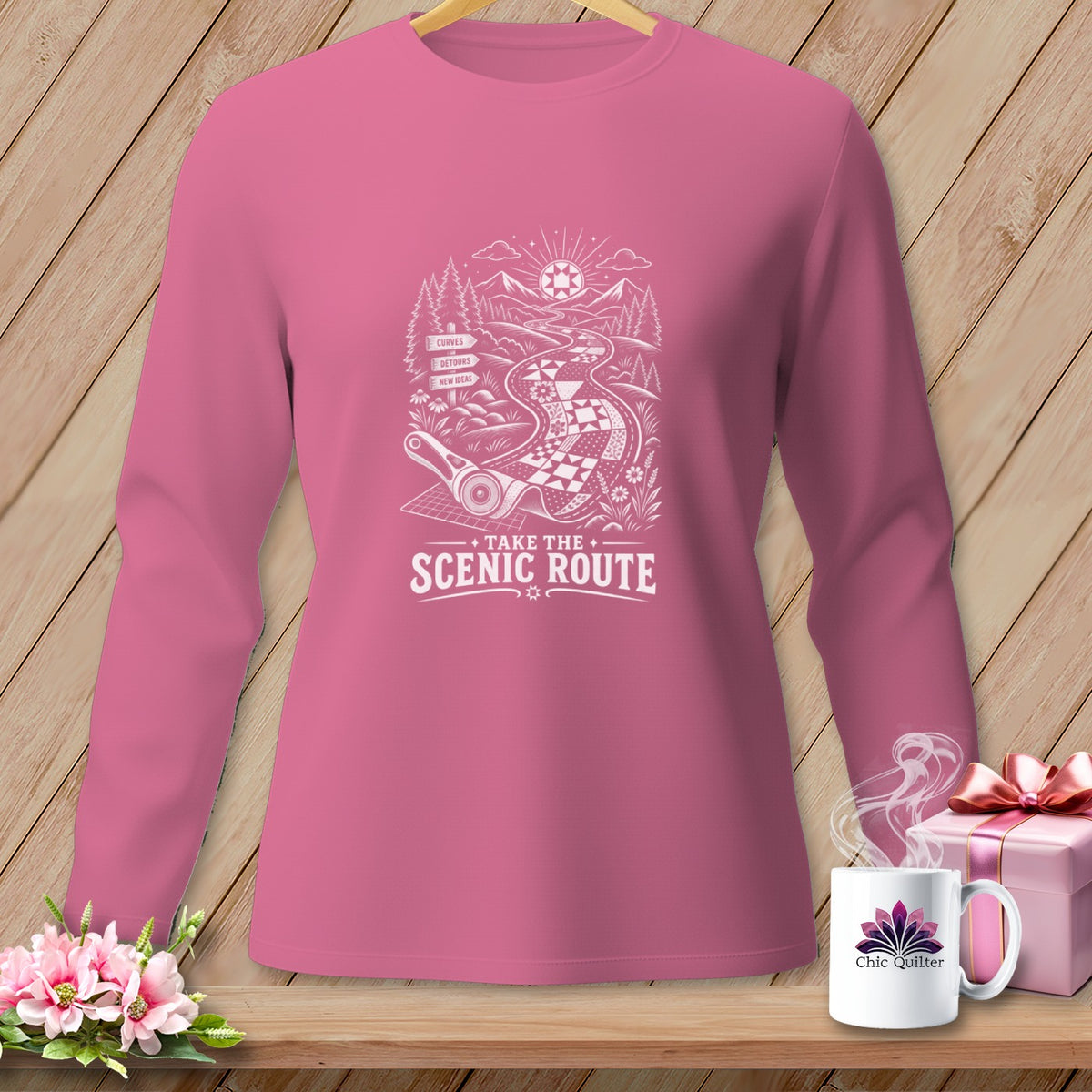 Pink long-sleeve shirt with "Take the Scenic Route" and a road design.