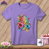 A purple t-shirt features a colorful watercolor thimble surrounded by flowers on a wooden background.