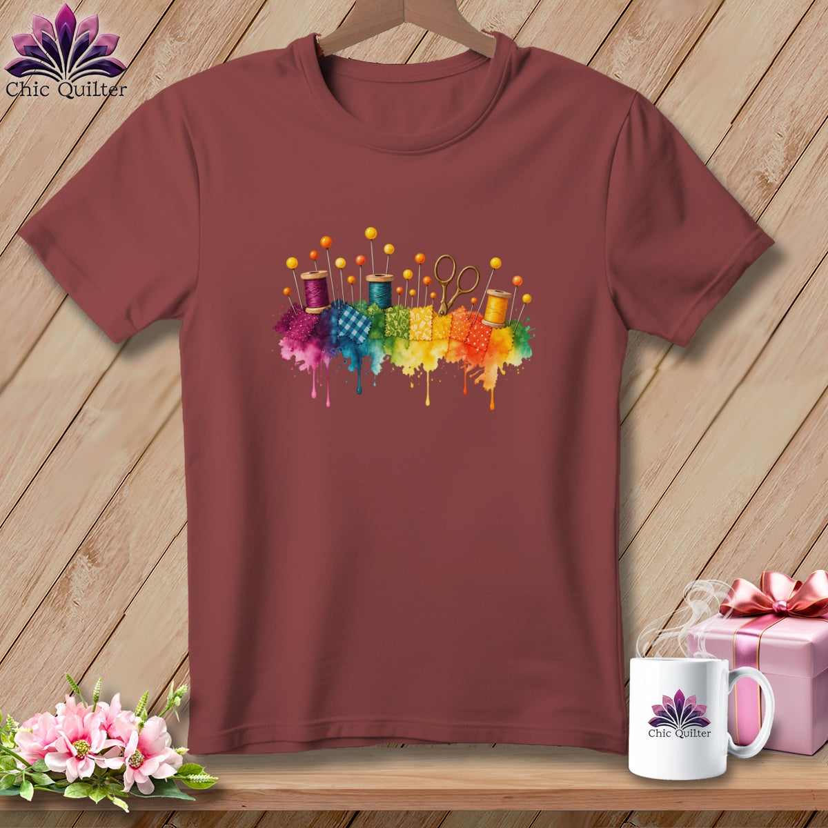 Maroon t-shirt with watercolor quilting supplies and rainbow paint splatters.