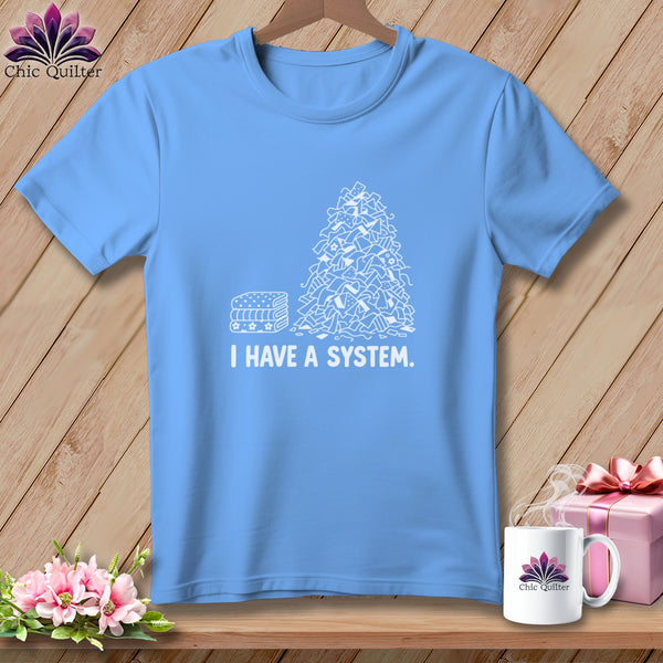 Blue t-shirt with white graphic of a pile of fabric scraps and "I HAVE A SYSTEM." text.