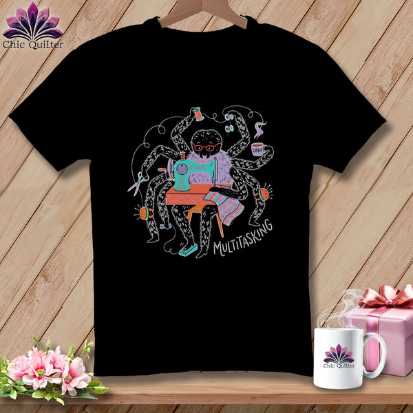 Black t-shirt graphic of a spider sewing, holding scissors, and drinking coffee.