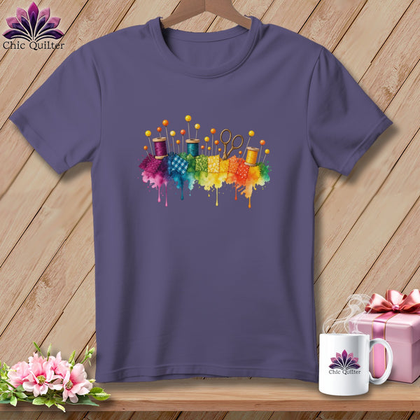 Purple t-shirt with watercolor sewing notions and fabric squares across chest.
