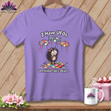 A purple t-shirt featuring a cartoon hedgehog with floating quilted UFOs and the text I Have UFOs Unfinished Fabric Objects.