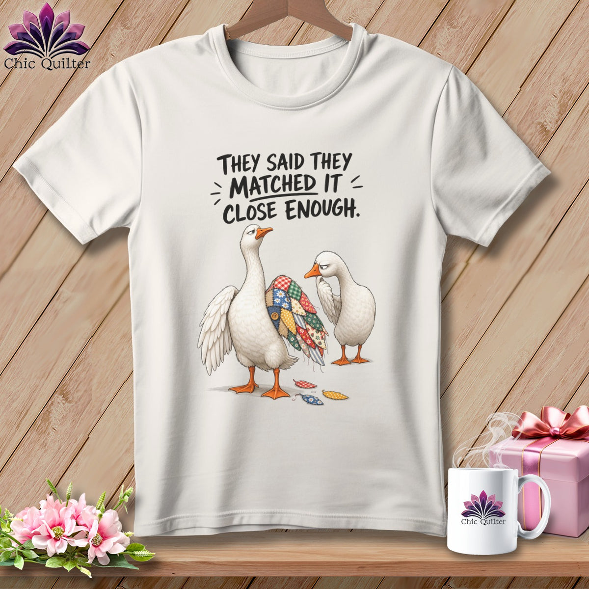 White t-shirt featuring two geese, one with a patchwork wing, and text.