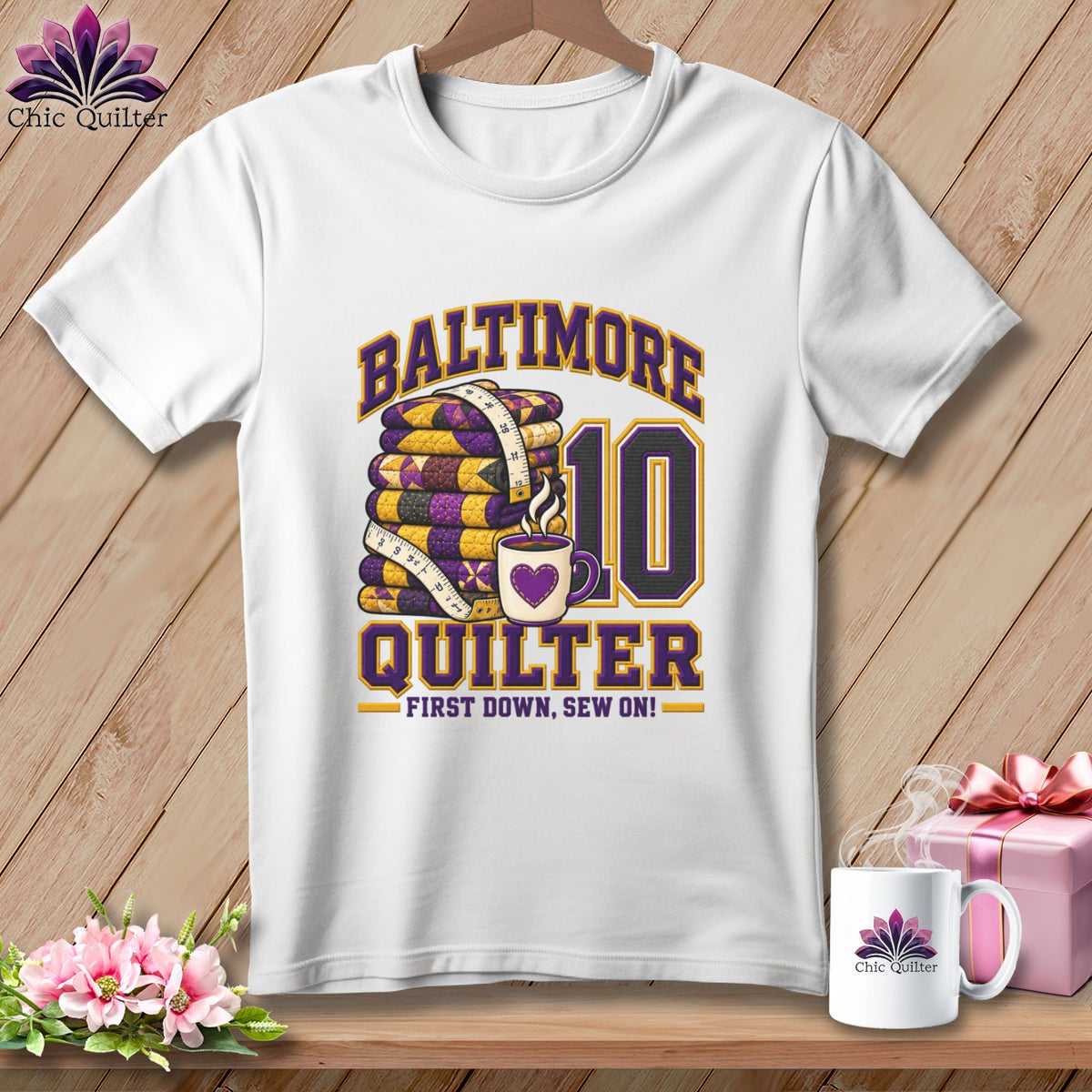 White t-shirt hanging on a wooden wall featuring Baltimore Quilter and number 10 graphics.