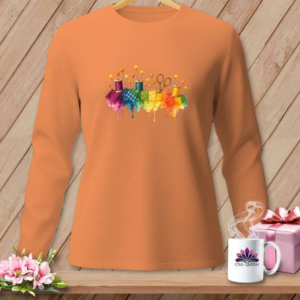 Orange long-sleeve shirt with watercolor sewing supplies graphic.