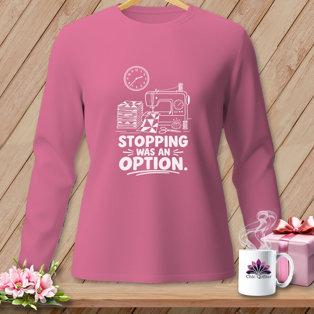 Pink long-sleeve shirt with white graphic of a sewing machine, fabric stacks, and the text "Stopping Was An Option".