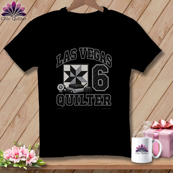 A black t-shirt featuring a Las Vegas Quilter graphic with a quilt block and rotary cutter.