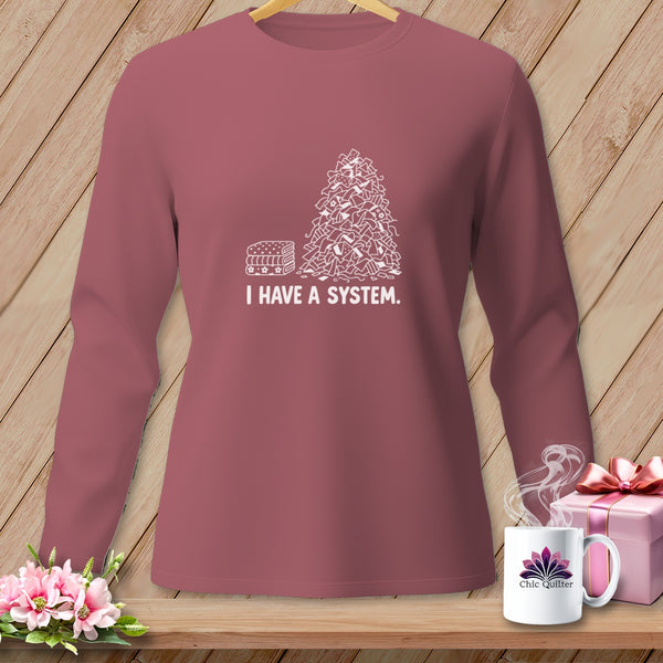 Pink long-sleeve shirt with "I HAVE A SYSTEM" and stacked fabric illustration.
