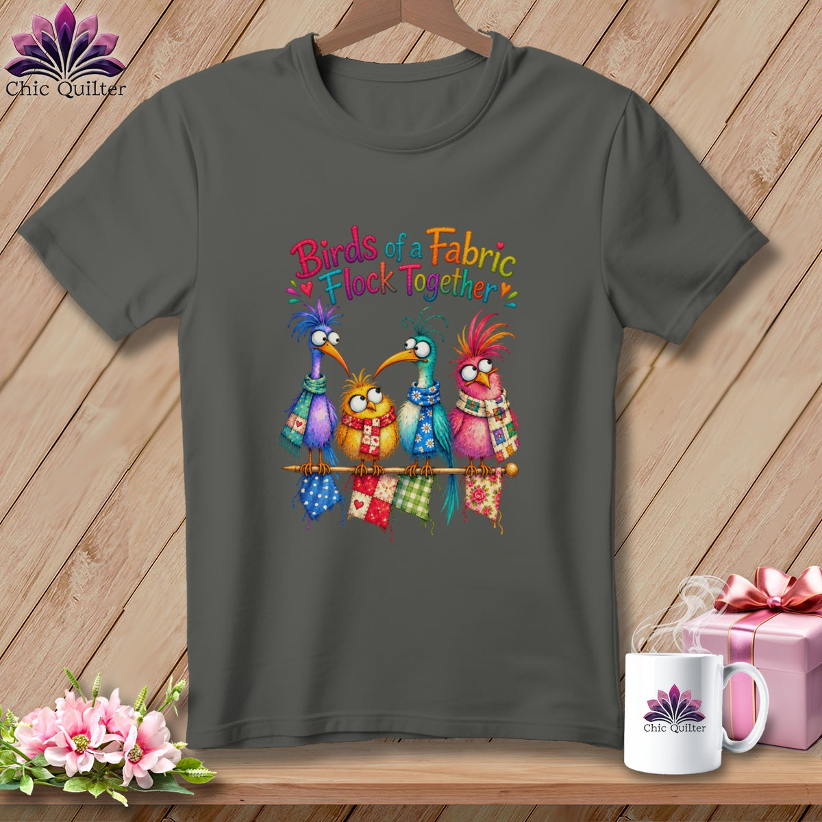 Charcoal t-shirt featuring four colorful whimsical birds on a perch with text reading Birds of a Fabric Flock Together.
