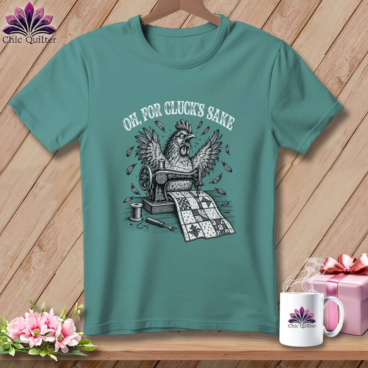 Teal t-shirt with a chicken sewing a quilt, with "Oh, For Cluck's Sake" text.
