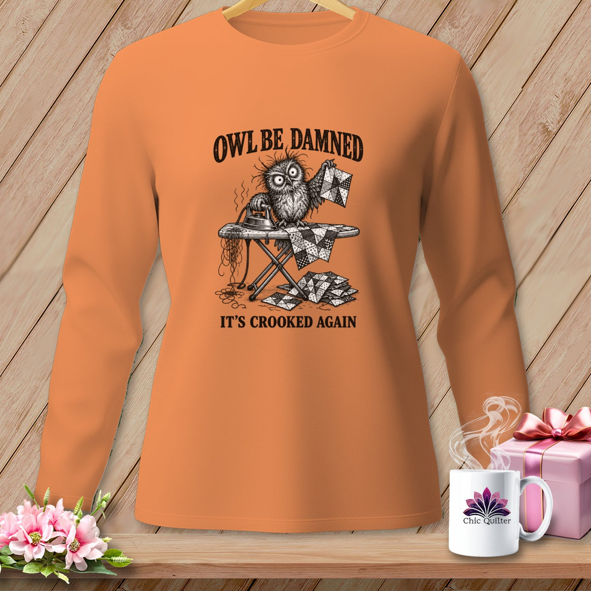 T-shirt with a graphic of a frustrated owl ironing a crooked quilt, reading "Owl be damned, it's crooked again."