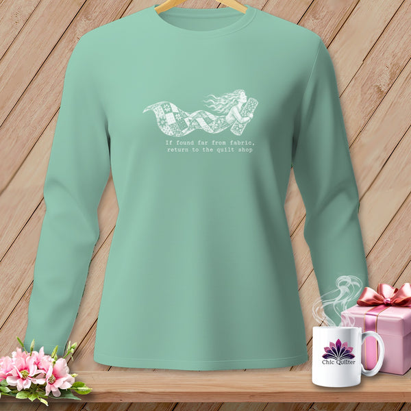 Teal long-sleeved shirt with white graphic of a woman and quilt saying "If found far from fabric, return to the quilt shop."