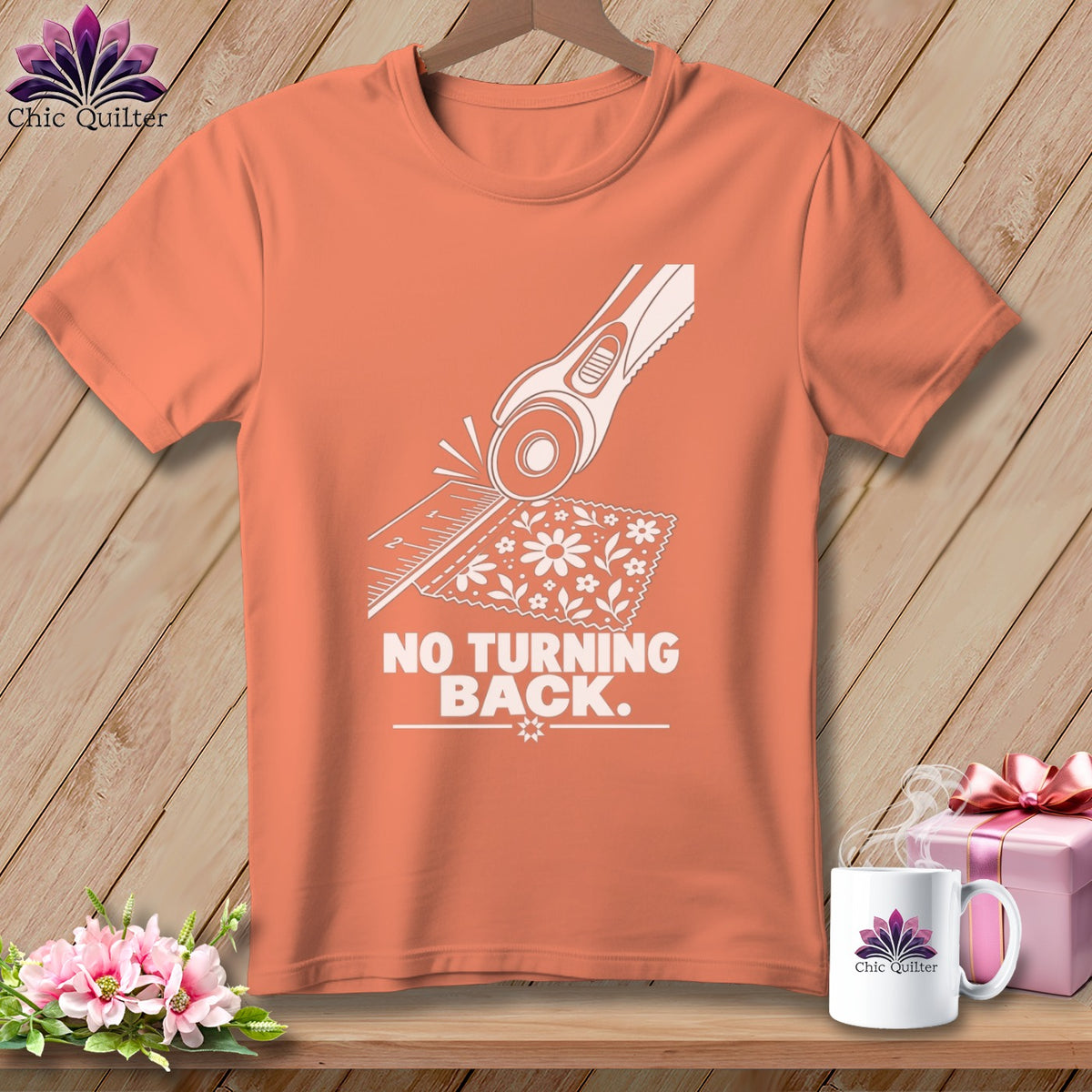 Orange t-shirt with white graphic of rotary cutter, ruler, fabric, and text "NO TURNING BACK."