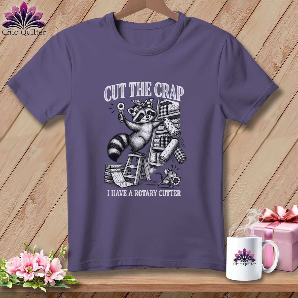 T-shirt with raccoon holding rotary cutter, stack of fabrics, and mouse. "CUT THE CRAP I HAVE A ROTARY CUTTER".