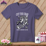 T-shirt with raccoon holding rotary cutter, stack of fabrics, and mouse. 