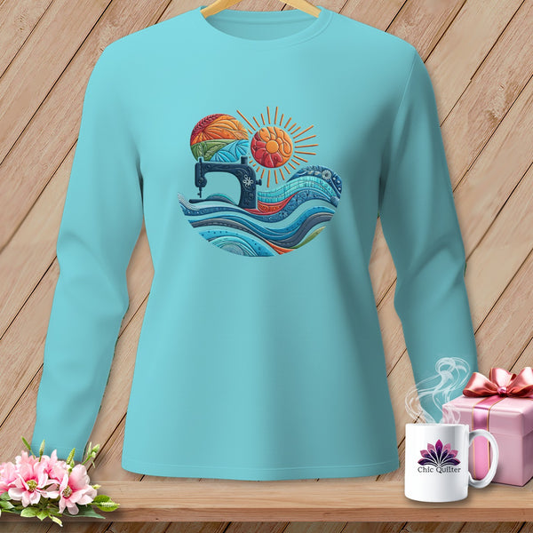 A turquoise long-sleeve shirt displays a circular graphic featuring a vintage sewing machine, stylized waves, and a sun.
