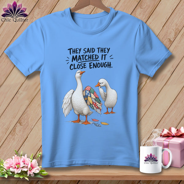 Blue t-shirt with geese wearing patchwork and text "They said they matched it, close enough."