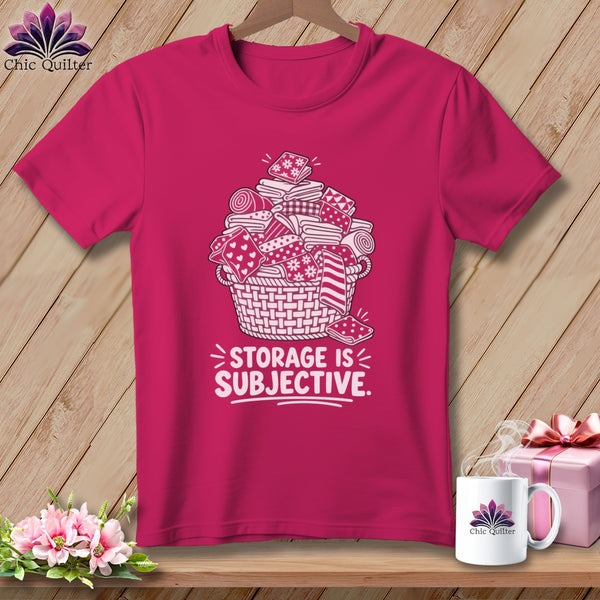 Pink t-shirt with white graphic of overflowing basket of fabric and text "STORAGE IS SUBJECTIVE."