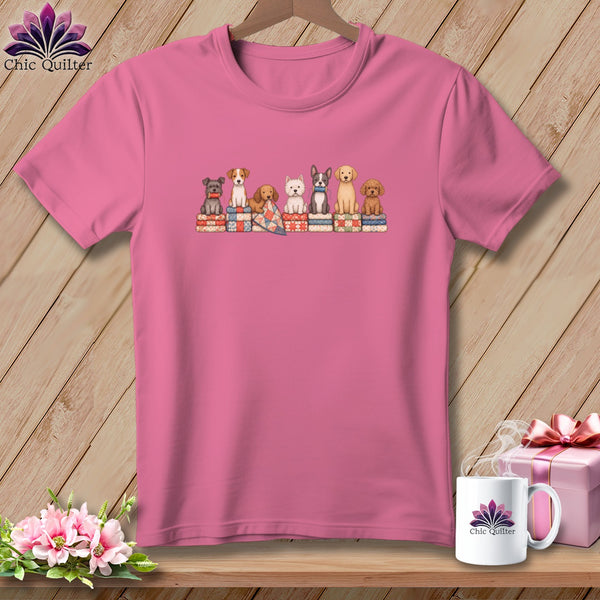 Pink t-shirt with a graphic of seven puppies sitting on colorful quilts.