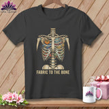 Dark gray t-shirt with a skeleton ribcage filled with fabric and sewing items. Text reads 