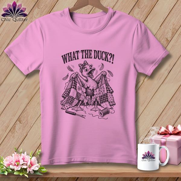A pink t-shirt with a cartoon duck holding a torn quilt, featuring the text "WHAT THE DUCK?!".