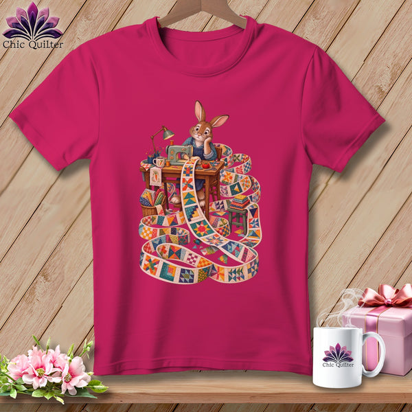 Rabbit sewing a long, colorful quilt strip on a t-shirt.