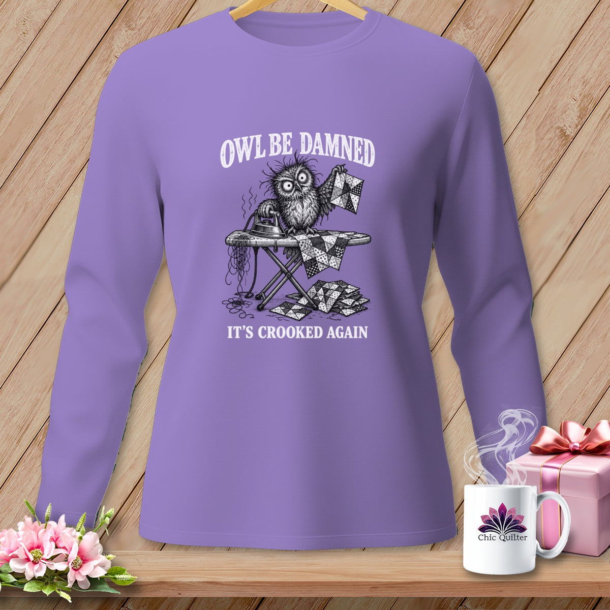 Purple long-sleeve shirt with an owl ironing a quilt. Text says "Owl Be Damned, It's Crooked Again".